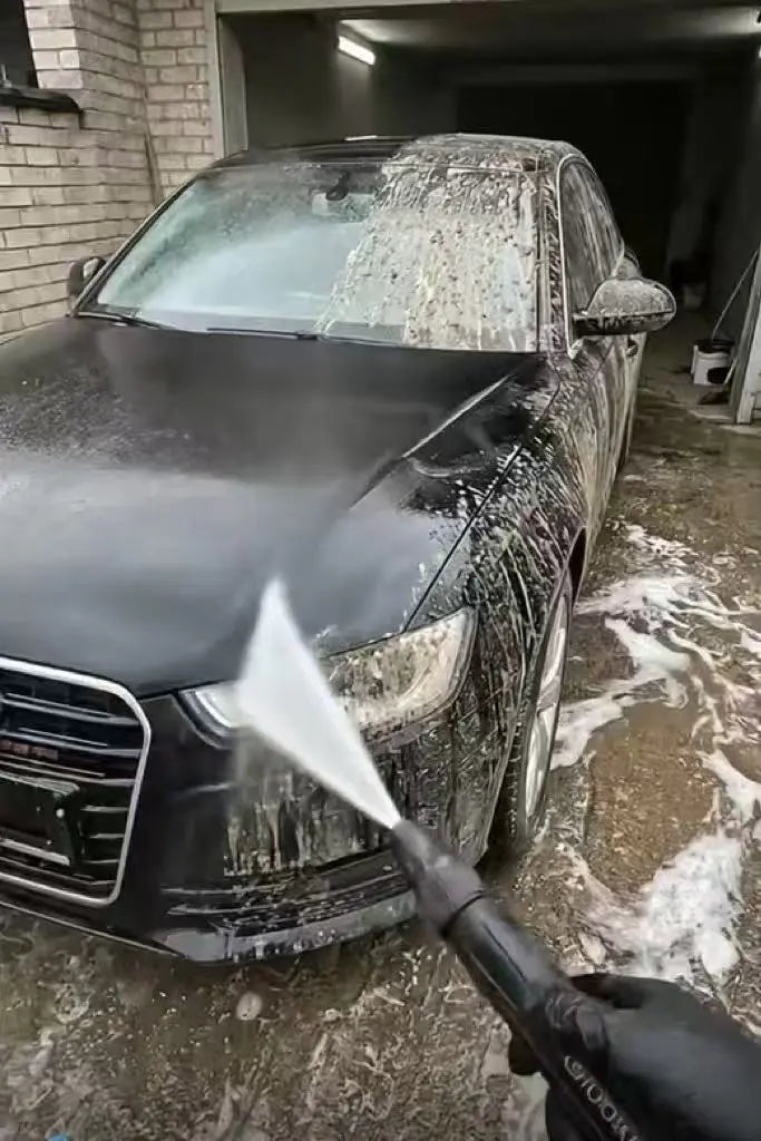 High-pressure water nozzle cleaning a dirty car with powerful jet spray
